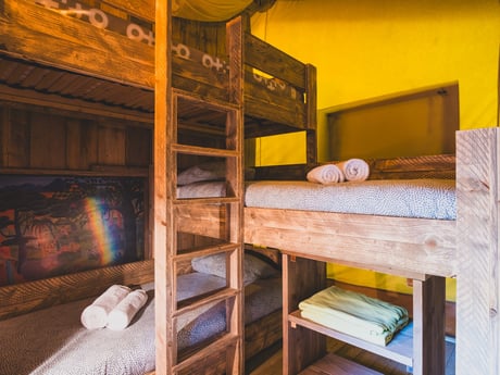 The canvas lodge features a triple bunk bed that comfortably sleeps three, making it ideal for families or groups.